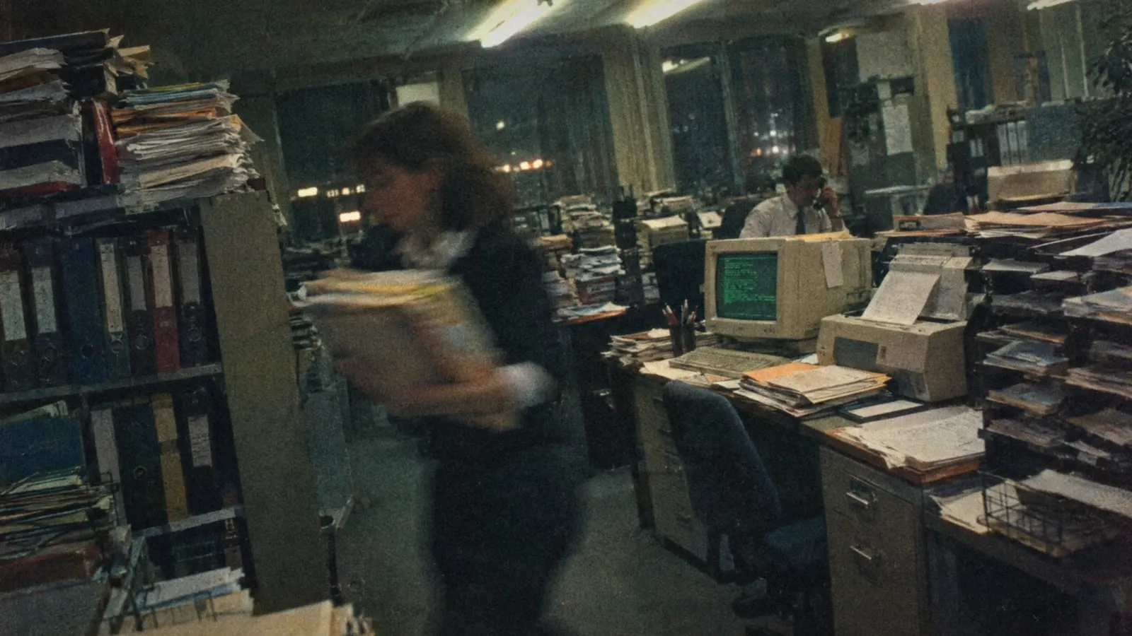 Paperwork and computer screens in an old bank back office.